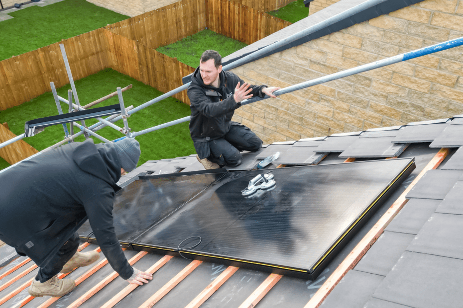 Working on a client's roof to install the solar panels. Two panels are installed with Dan and Jay nearby